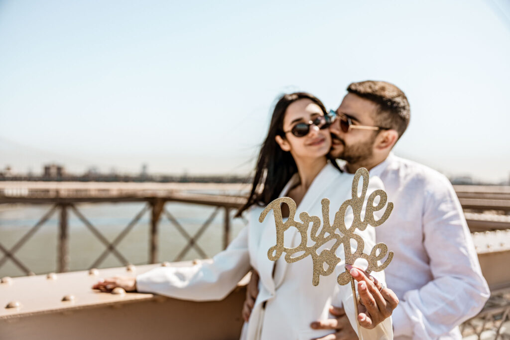 newly weds in New York City taking a photo on Brooklyn bridge