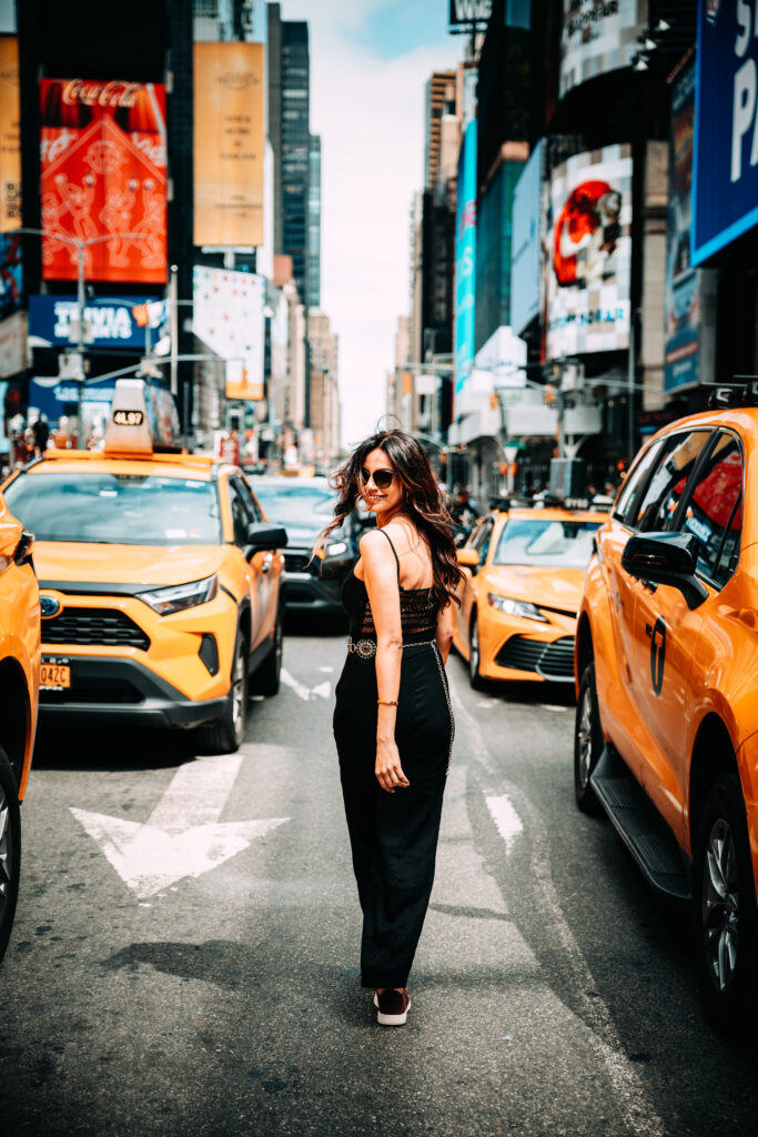 girl taking photos in times square with yellow cabs around her